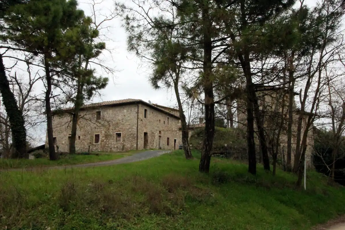 Edificio in pietra di Rencine, visto attraverso gli alberi in un ambiente rurale