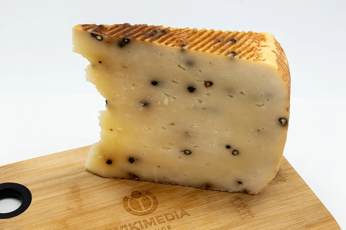Primo piano di un pezzo di formaggio stagionato tipo pecorino su tagliere