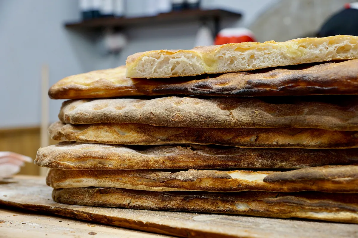 Pile di schiacciate o pane piatto appena sfornato su tavola di legno