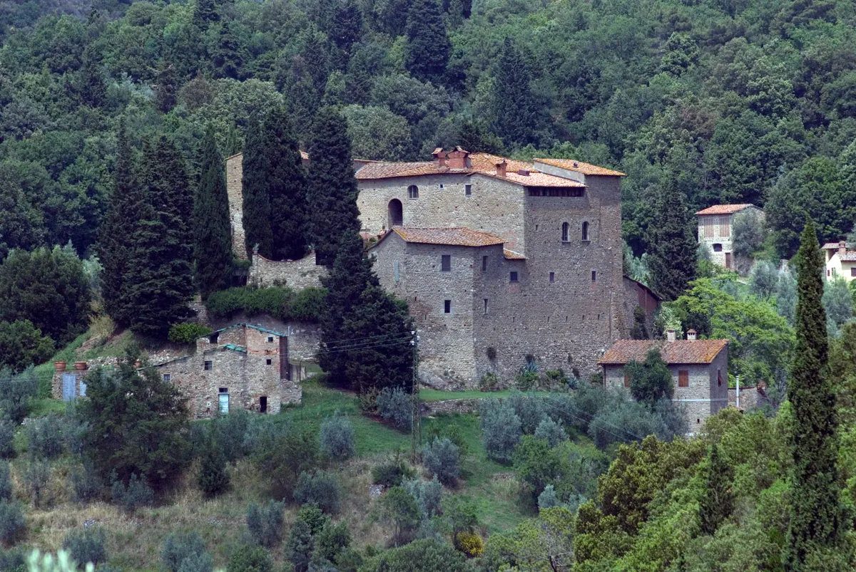 Veduta del Castello di Sezzate in pietra, circondato da cipressi e bosco