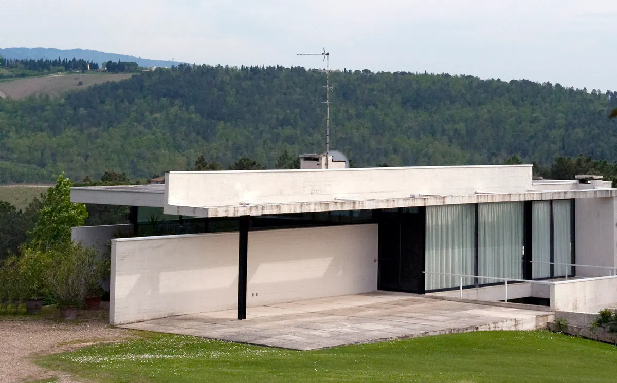 Villa moderna dalle linee razionaliste con terrazza, grandi vetrate e bosco sullo sfondo