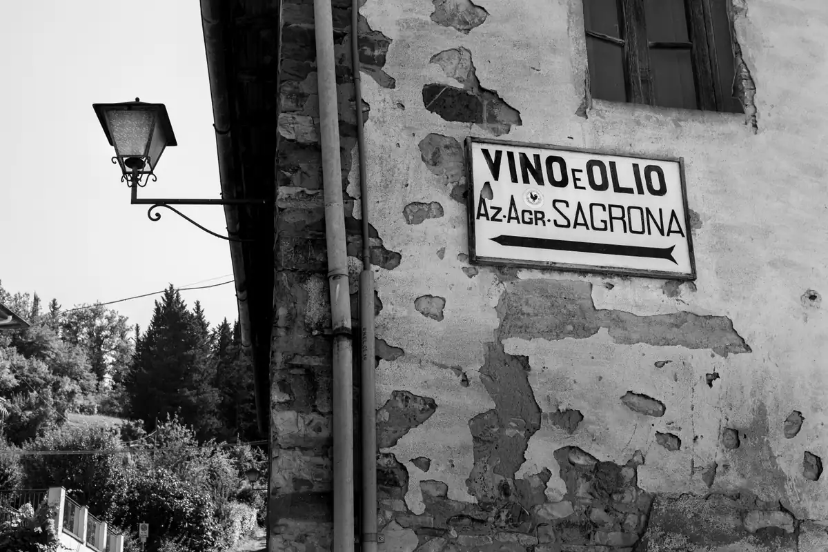 Facciata rustica in pietra con lampade d'epoca e insegne del borgo