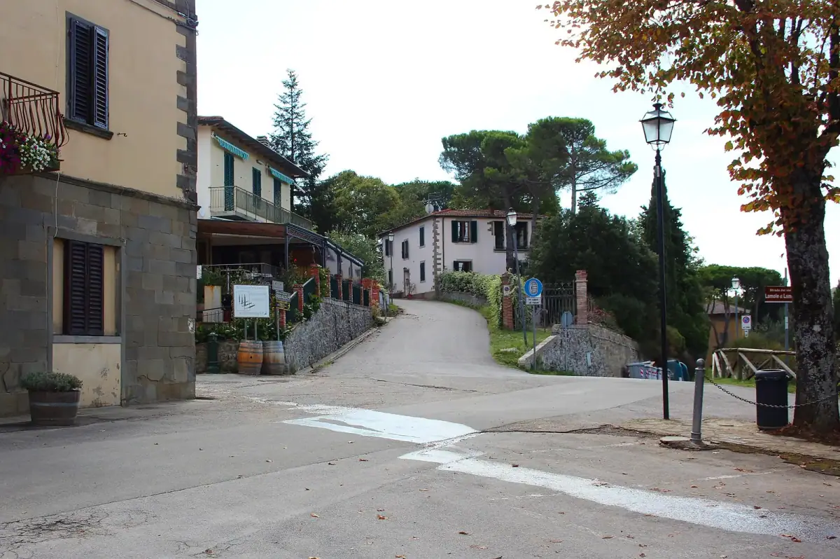 Stradina nel borgo di Lamole con case, lampioni e cartelli lungo la salita