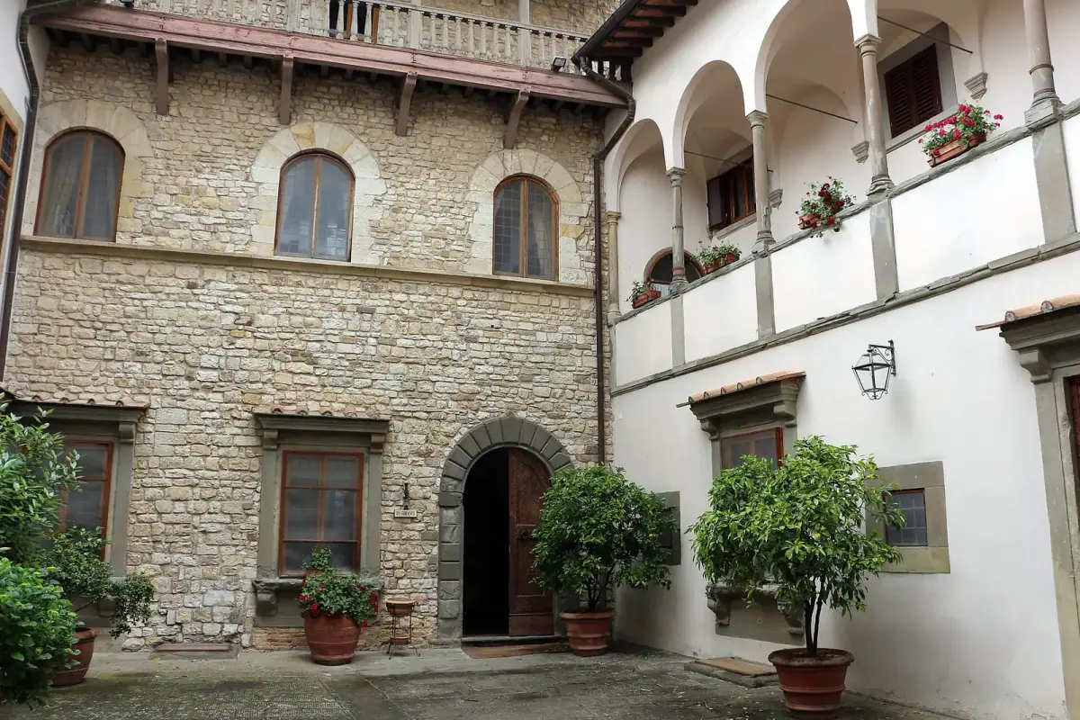Cortile interno in pietra del Castello Vicchiomaggio con archi, finestre e piante in vaso
