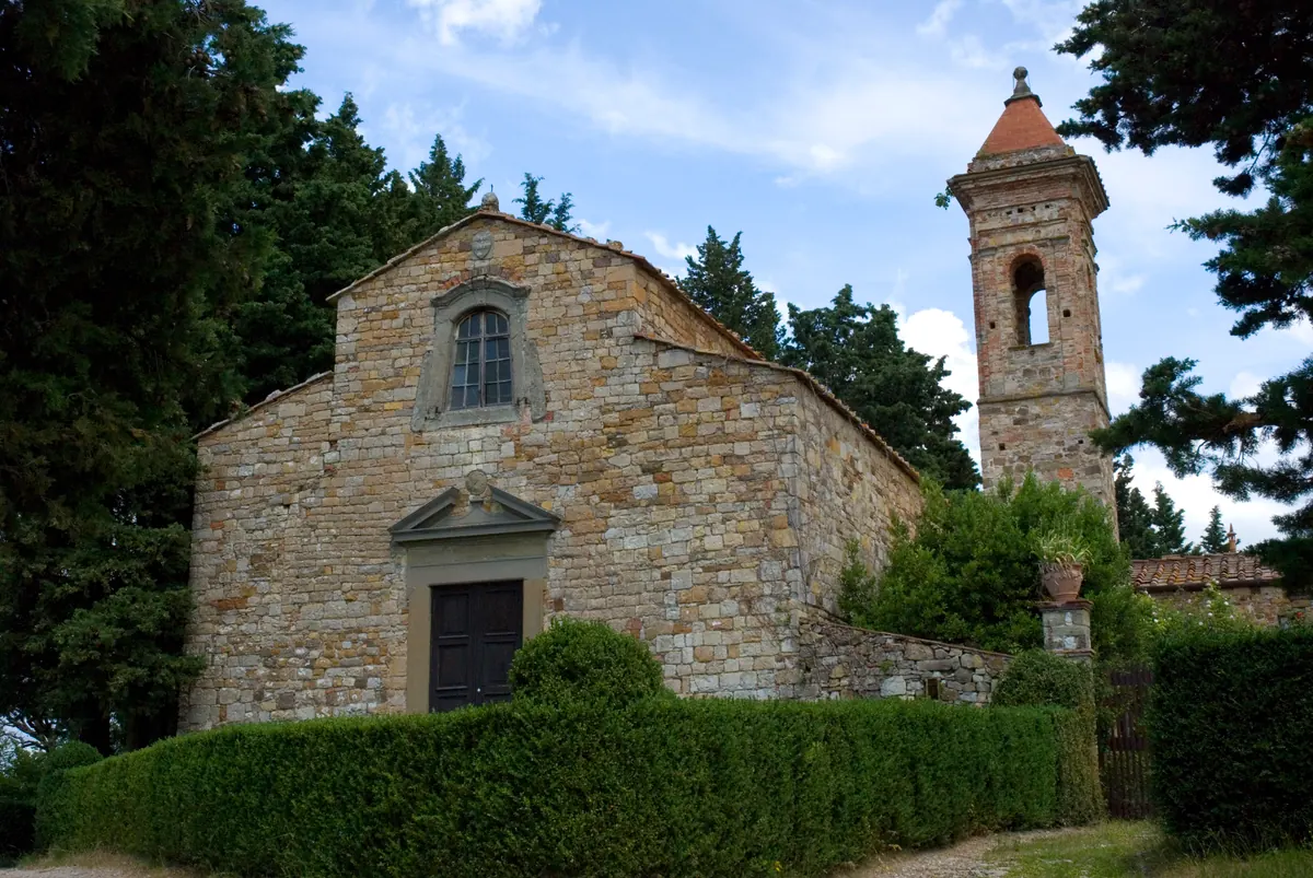 Pieve in pietra con facciata semplice e campanile tra gli alberi