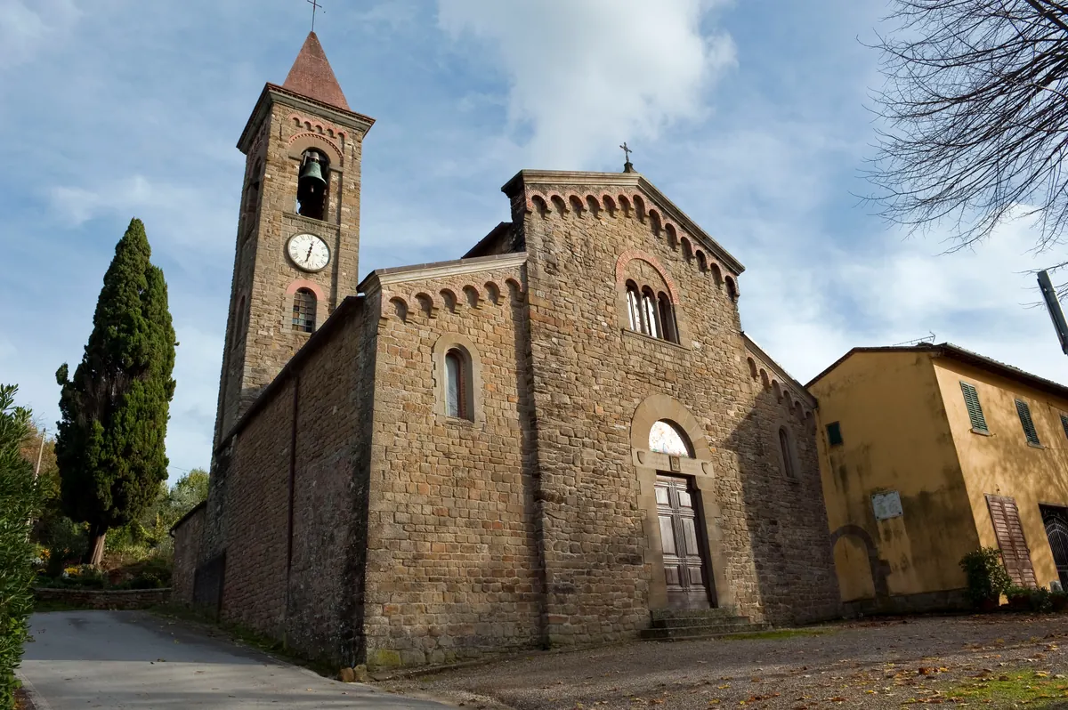 Facciata in pietra della Pieve di San Miniato a Rubbiana con campanile e cielo azzurro