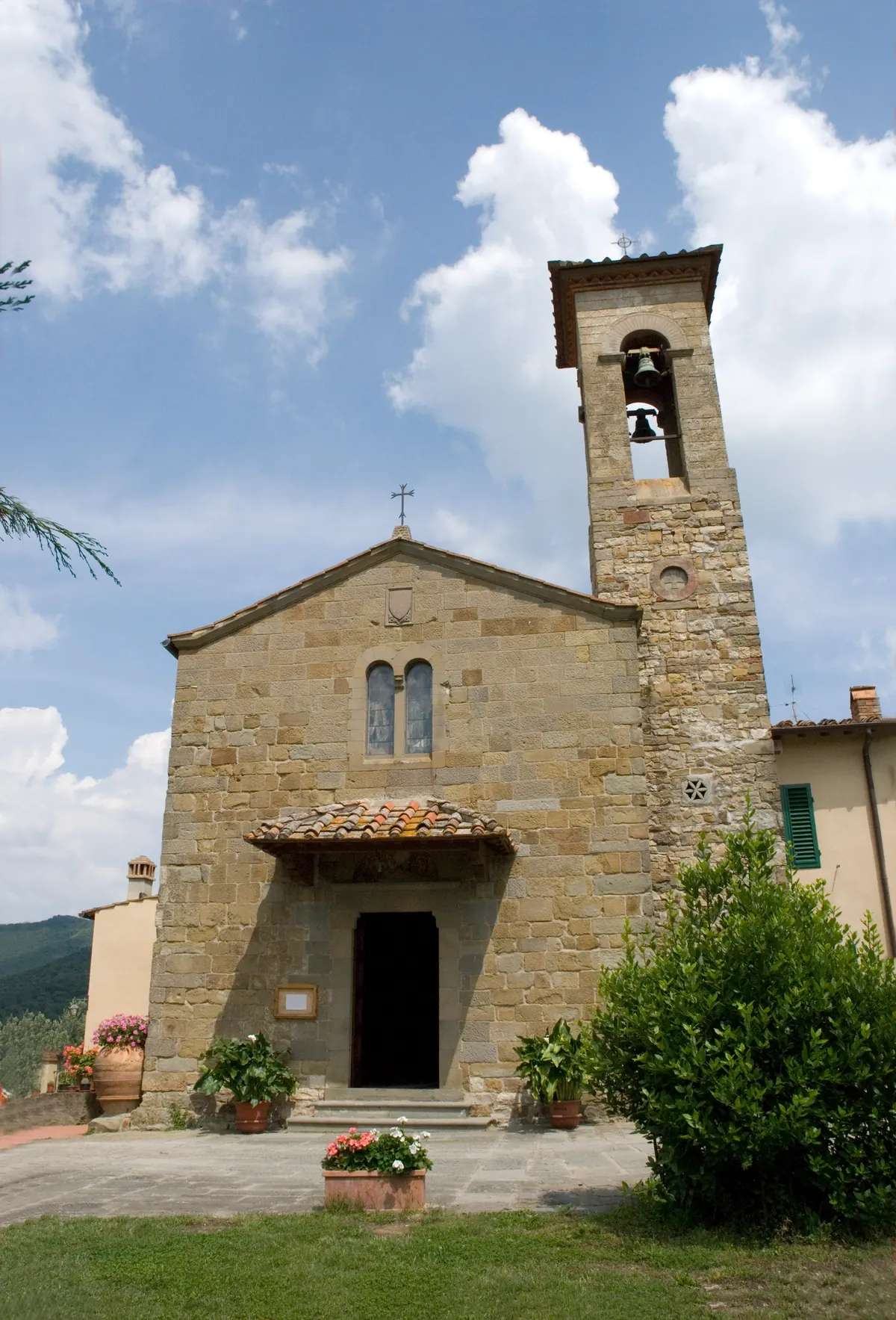 Facciata in pietra della Chiesa di San Donato a Mugnana con campanile sotto cielo azzurro