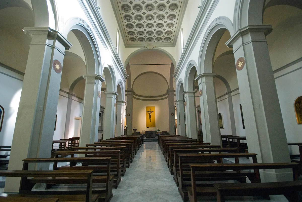 Interno della Propositura Santa Croce con navata, colonne, panche e altare