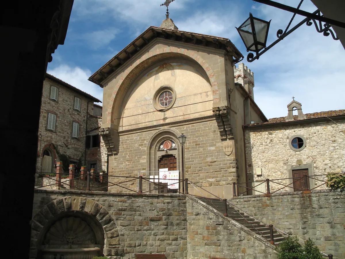 Facciata della Propositura di San Niccolò in pietra, vista da terra con scalinata e cielo nuvoloso