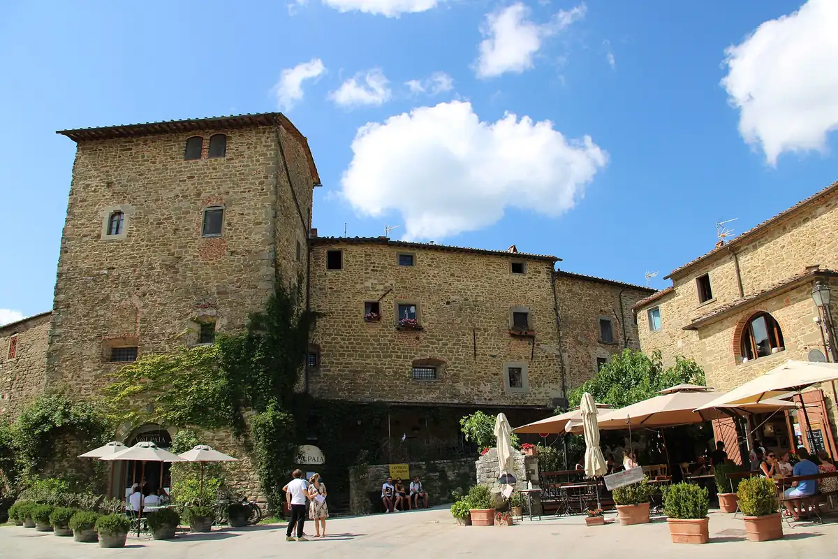 Castello di Volpaia in pietra con torre, piazzetta e dehors con ombrelloni