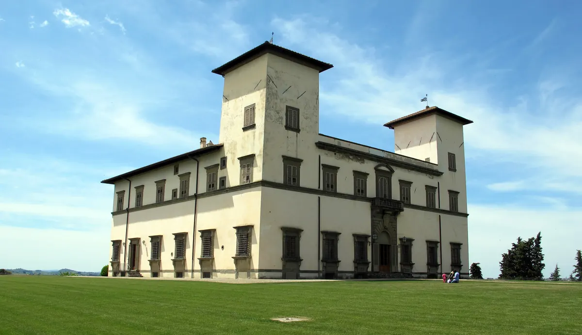 Villa Le Corti vista da terra, con facciata chiara, torri angolari e prato davanti